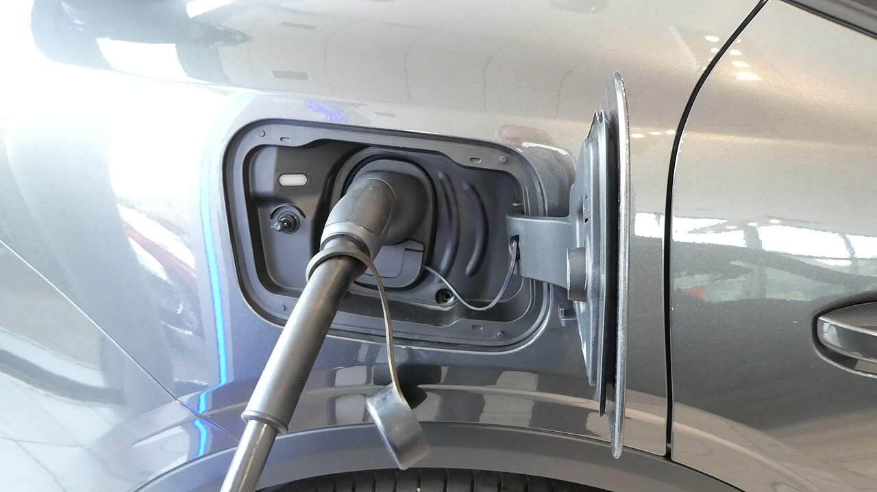 Coche eléctrico conectado a un punto de recarga con la pantalla mostrando el estado de carga