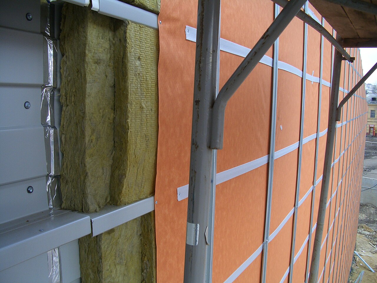 Operarios instalando paneles de aislamiento térmico por el exterior de una fachada